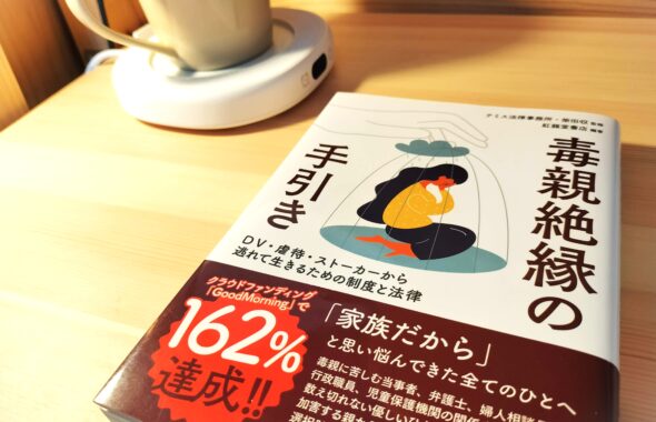 『毒親絶縁の手引き』書影。木の机の上に、珈琲カップとともに置かれている。